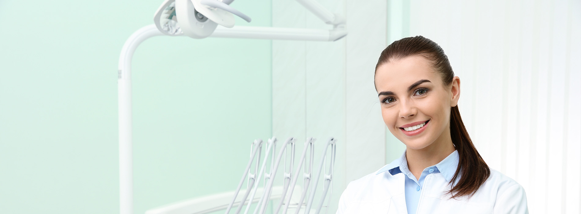 A young woman in a dental office, smiling at the camera.